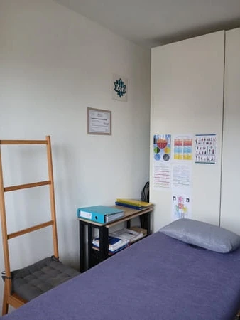 Cabinet de kinésiologie zen avec table de soin, ambiance apaisante et affiches colorées.