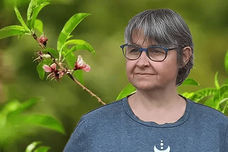 Portrait de Nathalie, praticienne en kinésiologie dans un décor vert et fleuri, ambiance zen.